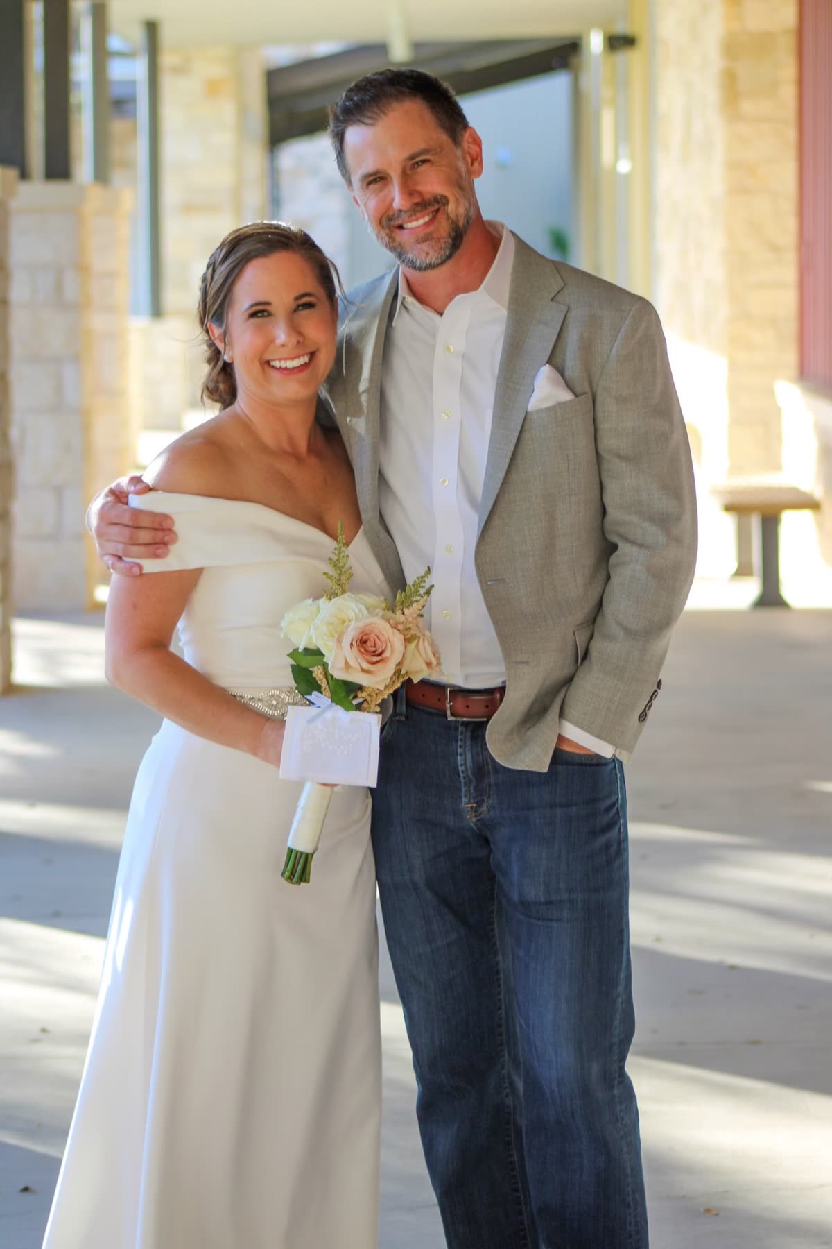 Carly and Brandon on their wedding day, Carly holding a small bouquet of cream roses.